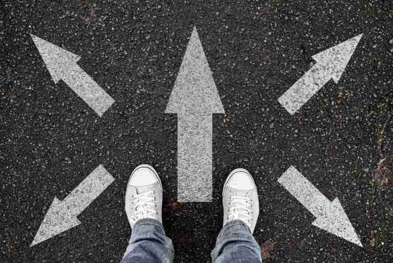 PersonStandingOnRoadWithArrowMarkingsPointingInDifferent | Professionelles Coaching in Düsseldorf – Bobach Coaching & Consulting Gute Entscheidungen mit Coaching treffen