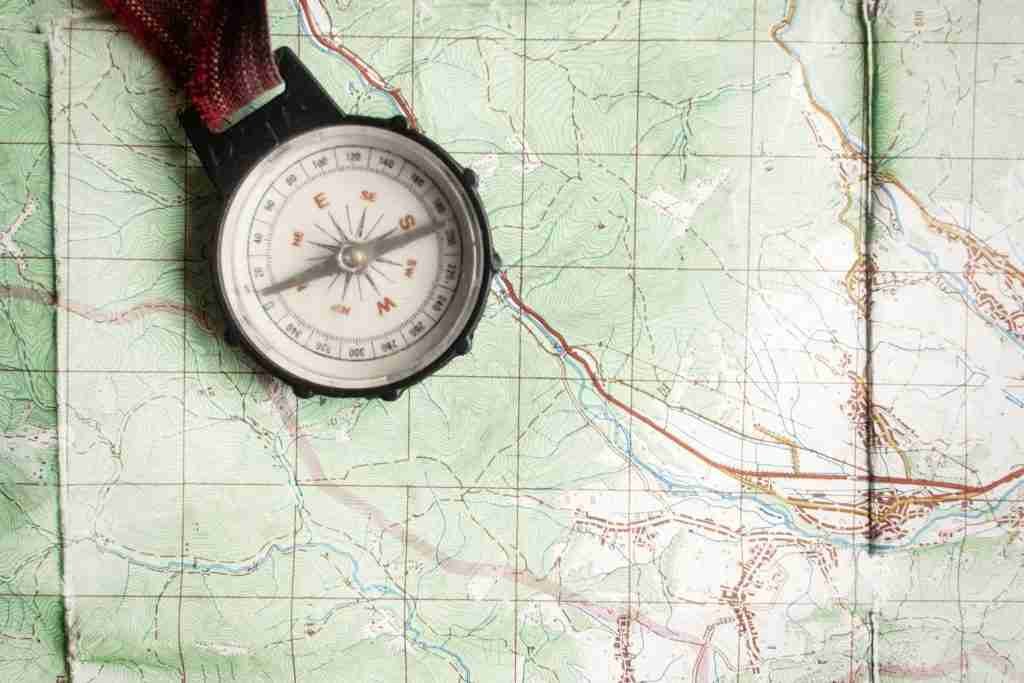 getty-images-8_B6VHqOkIE-unsplash | Professionelles Coaching in Düsseldorf – Bobach Coaching & Consulting Compass resting on a detailed topographic map with contour lines and trails, ready for navigation.记?
