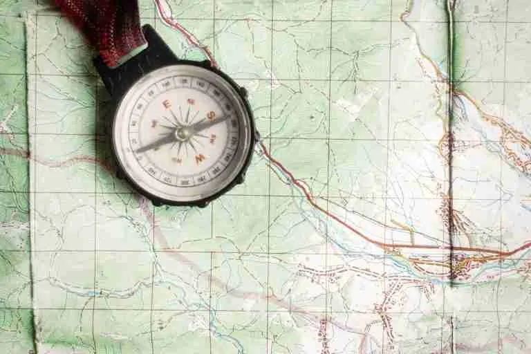 Compass resting on a detailed topographic map with contour lines and trails, ready for navigation.记?