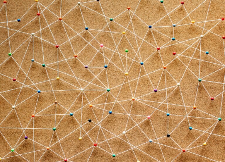 curated-lifestyle-MOJsQmZQHEk-unsplash | Professionelles Coaching in Düsseldorf – Bobach Coaching & Consulting Colorful pins and white strings on a corkboard forming a complex network of connections.